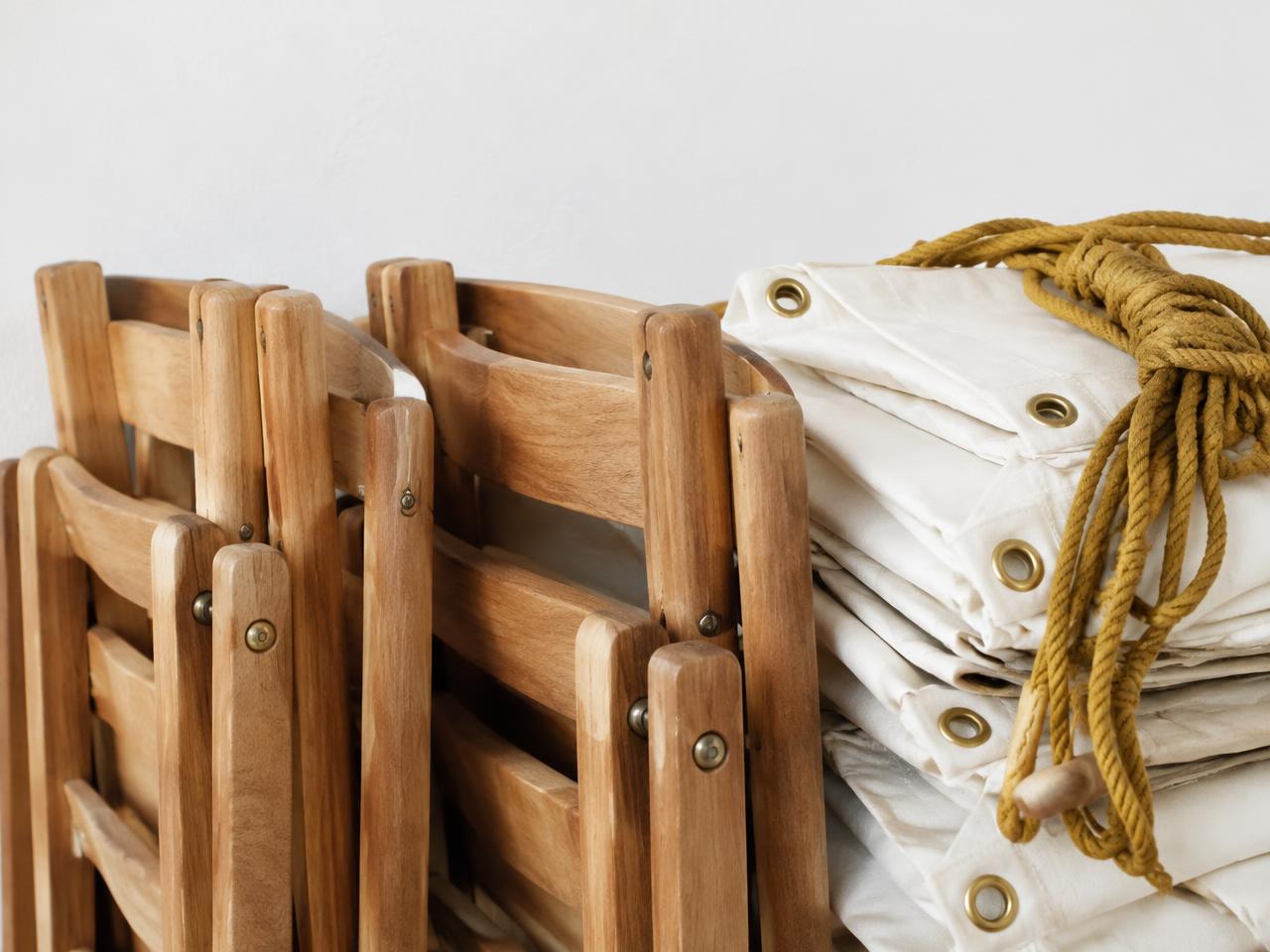 Sillas de madera plegadas y lonas blancas atadas con mecate ocre
